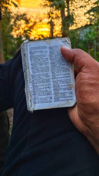 istock Men Holding English Dictionary On Hand With Sunset in Background 2184907352