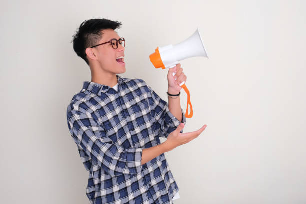 istock Young Asian man facing to the left announce something using megaphone with excited 2184908620