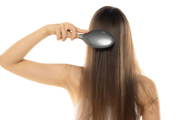 unknown young woman combs her long hair on white studio background