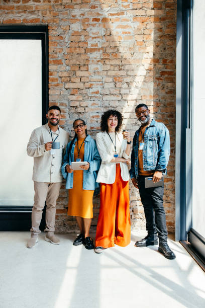 istock Stylish group of professionals standing cheerfully with tablets and coffee 2184910987