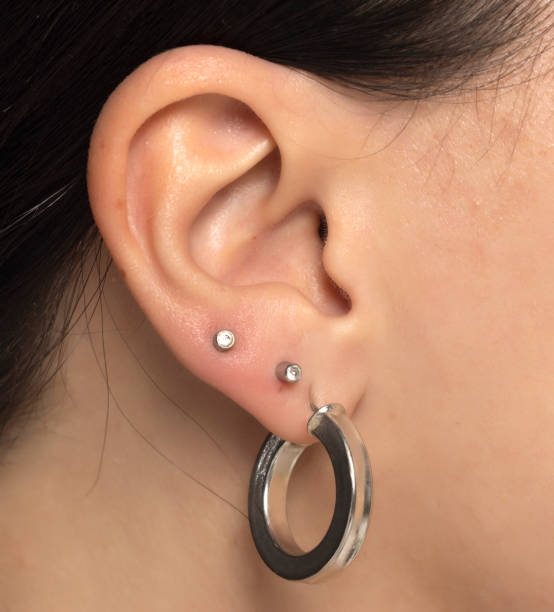istock Closeup of female ear with three earrings. 2184911278