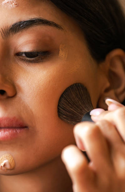 istock Pretty young make-up artist  is applying make-up base to her face with brush. 2184915287