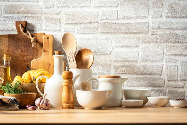 istock Kitchen table with white crockery and wooden utensils. Copy space on white bricks wall at background 2184915342