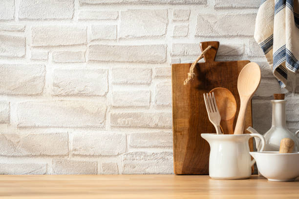istock Kitchen table with white crockery and wooden utensils. Copy space on white bricks wall at background 2184915343