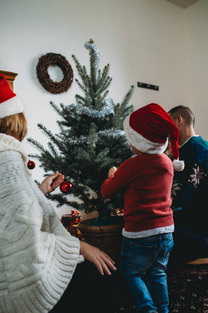 istock Family decorating christmas tree together at home 2184915385