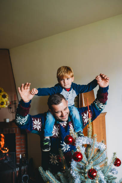 istock Father carrying son on shoulders decorating christmas tree at home 2184915452