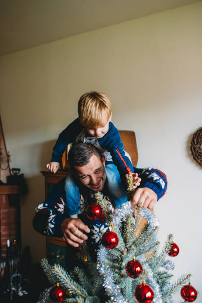 istock Father and son decorating christmas tree together at home 2184915472