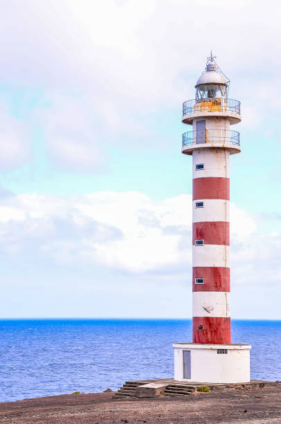 istock A lighthouse is standing on a rocky shoreline, overlooking the ocean 2184916205