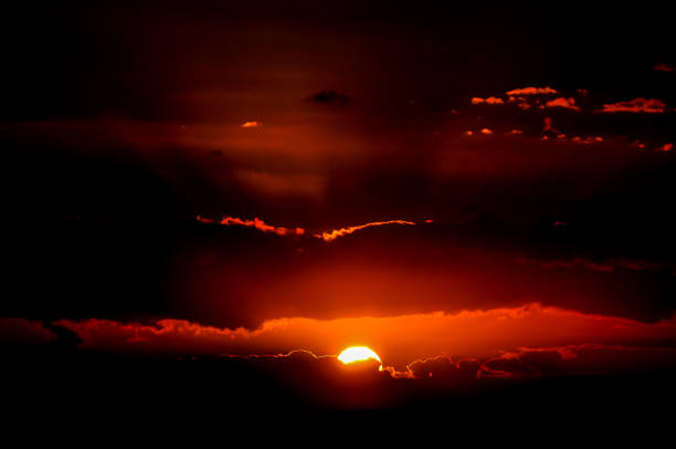 A sunset with a large sun in the sky. The sky is dark and the sun is orange