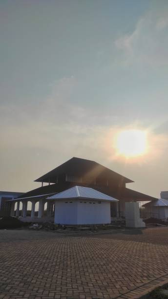 A partially constructed building under a hazy sky, with the sun shining through. The scene captures the progress and development in a spacious outdoor setting.