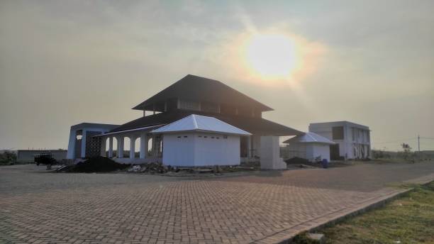 istock A partially constructed building under a hazy sky, with the sun shining through. The scene captures the progress and development in a spacious outdoor setting. 2184920789