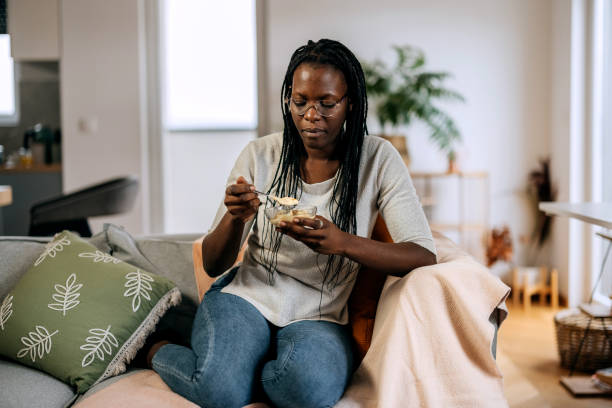 istock Casually clothed woman eating ice cream while relaxing on a sofa at home 2184924132