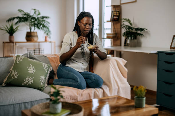 Casually clothed woman eating ice cream while relaxing on a sofa at home