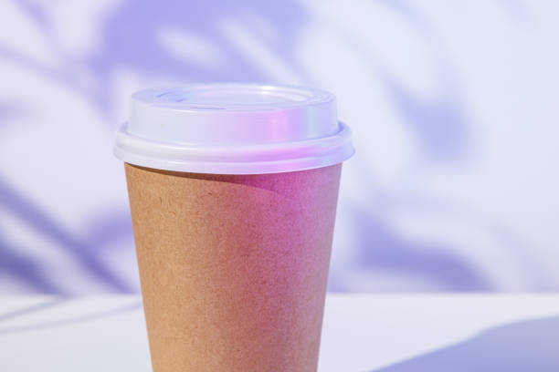Takeout coffee cup with foliage shadows, copy space, close up