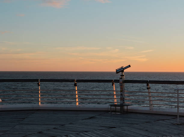 Binoculars at the edge of the pier in Scheveningen. Sunset, warm light, tranquil scene. The Hague, Netherlands.