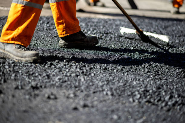 istock Construction worker laying asphalt on a roadway during daylight with protective gear and tools in use 2184929949