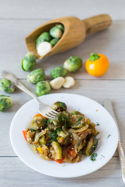 istock Brussel sprouts cooked with vegetables and spices, on a wooden table 2184931535