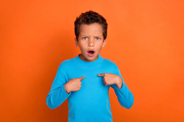 istock Photo of astonished dissatisfied boy hand arm direct himself misunderstanding why problem trouble isolated on orange color background 2184931953