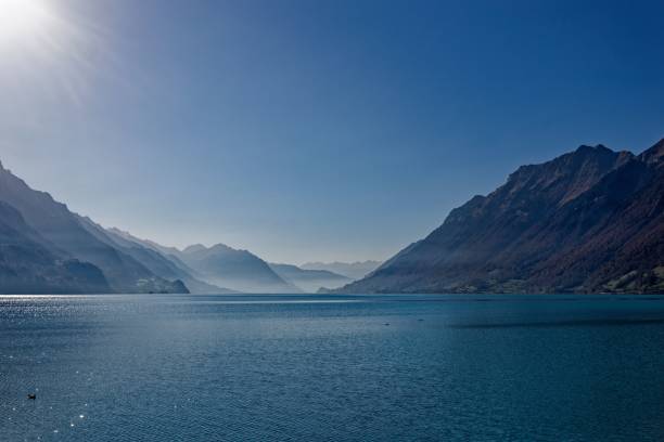 A serene view of Lake Brienz with surrounding mountains under a clear blue sky in Switzerland.