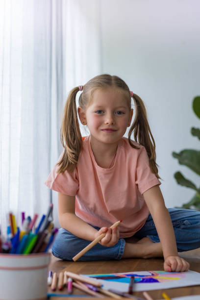 istock With smile 5-year-old girl giggles while creating art at the table with vibrant colored pencils 2184933473