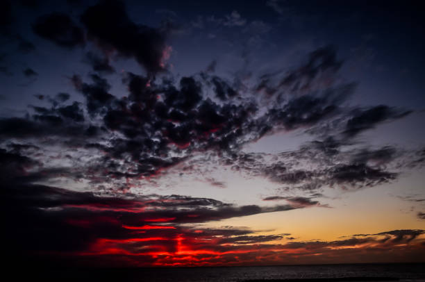 The sky is dark and cloudy with a red sun setting in the background. The clouds are thick and the sky is filled with them