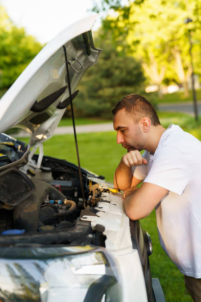 istock Young stressed man having trouble with his broken car looking in frustration at failed engine 2184936631