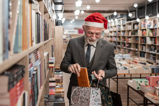 istock Elderly Man Searching Bookshelves in Santa Hat 2184937694