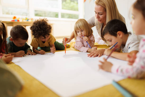 Children draw together with their kindergarten teacher