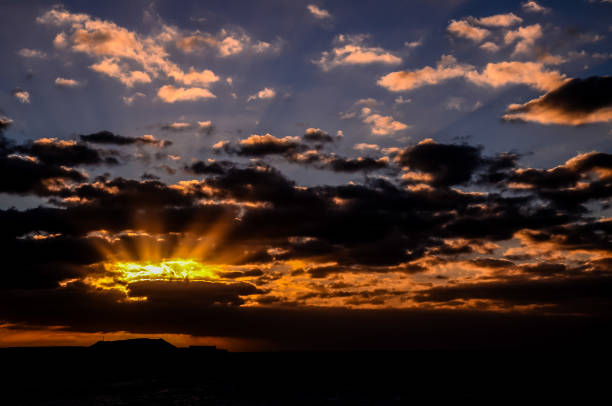 istock The sky is dark and cloudy with a bright sun shining through the clouds 2184938615