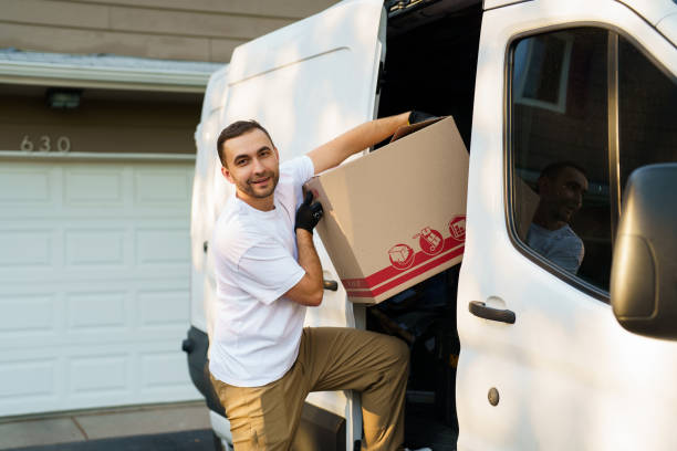 istock Young delivery man loading cardboard boxes from truck 2184942486