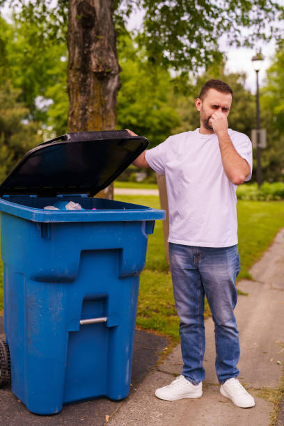 istock Young man show the bad smell emanating inside a large plastic mobile trash bin. 2184943159