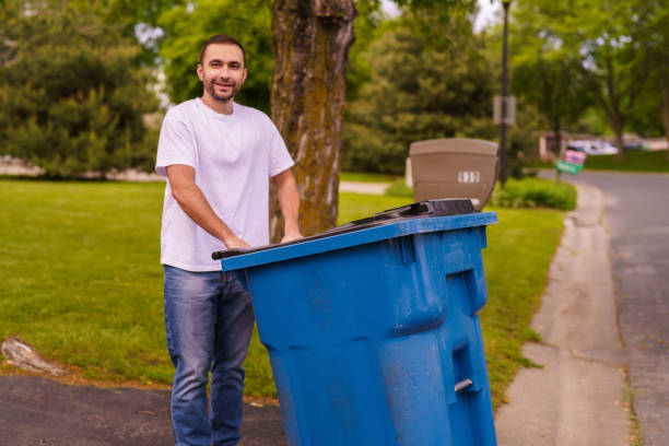 istock Young man pushes a large green plastic trash bin for weekly waste disposal schedule. 2184943236