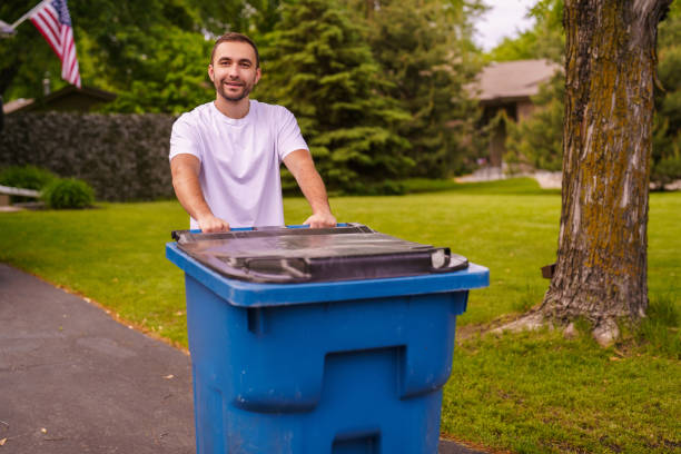 istock Young man pushes a large green plastic trash bin for weekly waste disposal schedule. 2184944052