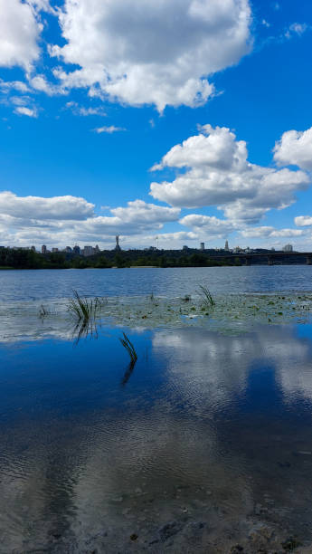 istock Clear Blue Sky Reflected on Calm River with Cityscape 2184945069