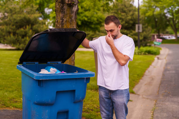 istock Young man show the bad smell emanating inside a large plastic mobile trash bin. 2184945457