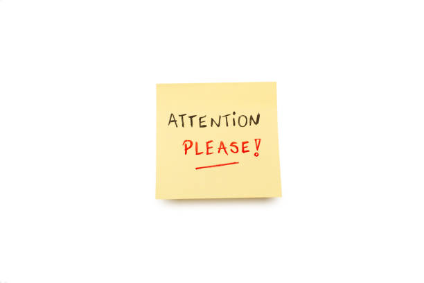 Attention please handwritten on a yellow sticky paper on a white background with copy space