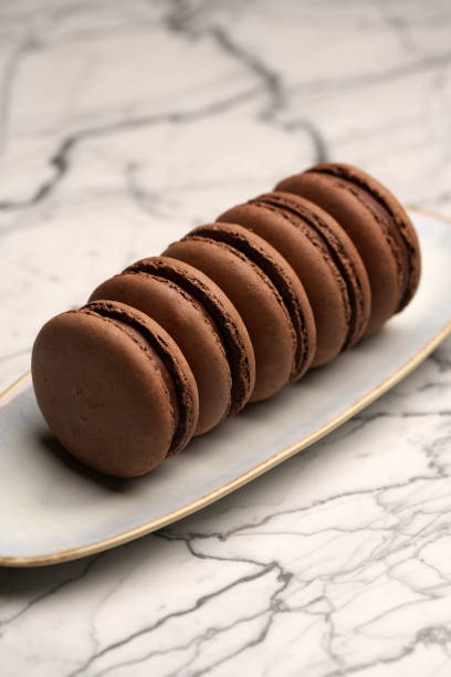 istock Chocolate macaron dessert. Brown macaroon with chocolate cream on a white plate 2184953634