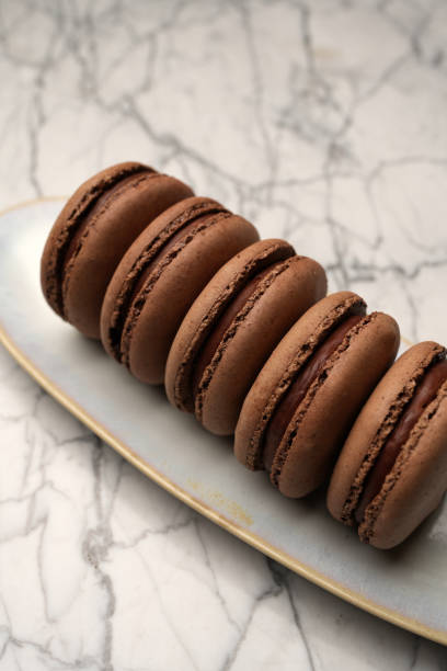 Chocolate macaron dessert. Brown macaroon with chocolate cream on a white plate