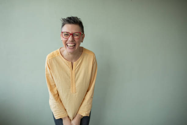 Portrait of a charming short haired mid adult woman standing in front of a green background in studio.