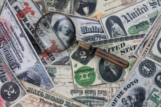 istock Retro vintage US banknotes and silver certificates with silver dollar coins and magnifying glass 2184955944