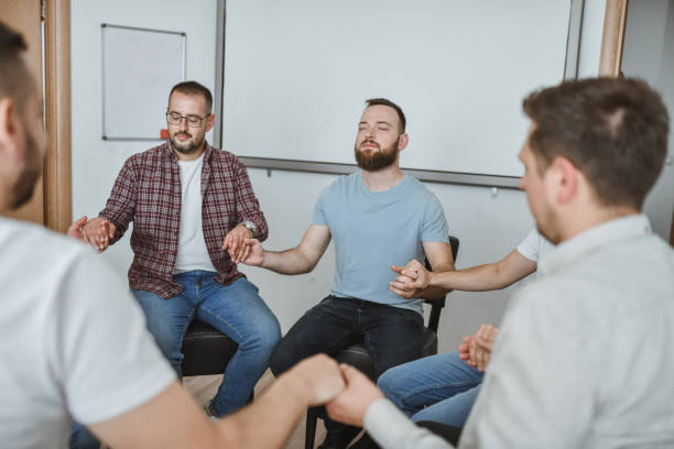 istock Handsome Males Being Vulnerable in Support Group Holding Hands and Praying With Closed Eyes 2184957329
