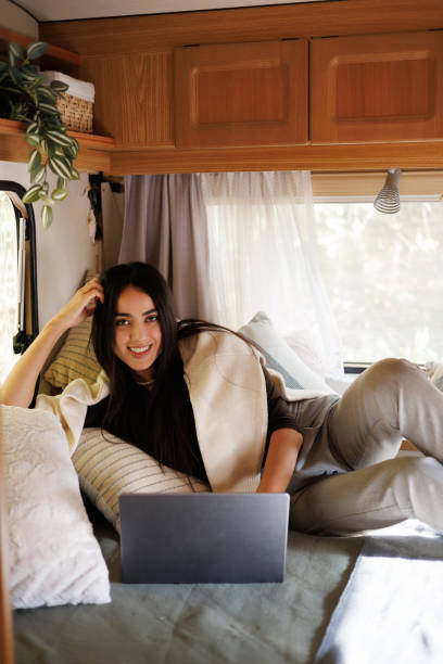 istock Young woman using laptop computer on bed of a camper RV van 2184958127