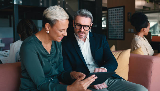 istock Business people, hotel and lounge with tablet, communication and management on sofa. Technology, planning and brand consultant meeting with discussion of public relations opportunity on web app 2184958482