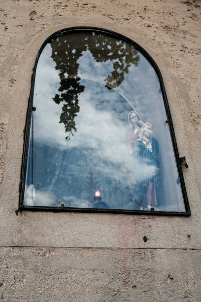 Reflection of a Religious Statue Behind an Arched Window