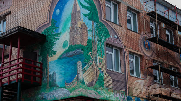 Barentsburg, Svalbard and Jan Mayen Islands - September 20, 2024: A vibrant mural adorns the exterior of a building in Barentsburg, showcasing a scenic landscape with a tower, forest, and water. The artwork reflects the areas rich history and culture.