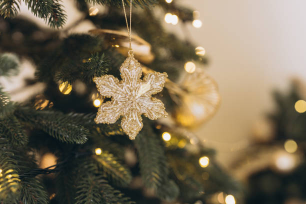 istock Golden snowflake ornament hanging on christmas tree with lights 2184979184