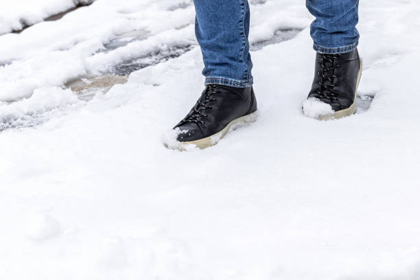 istock man in black leather boots walking on white snow. 2184979514