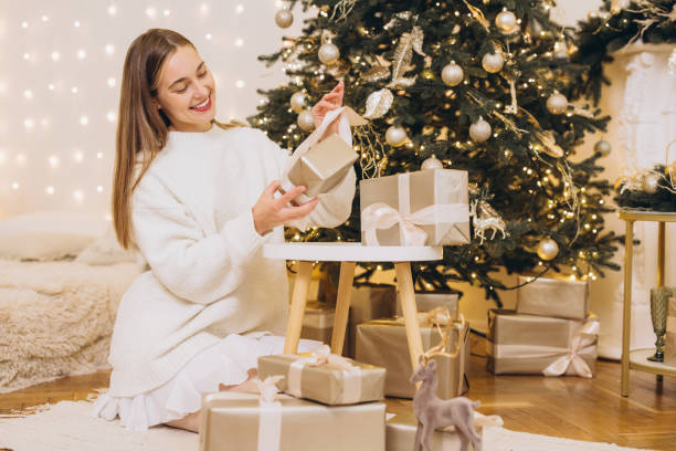 istock Woman arranging christmas gifts under decorated tree 2184981759