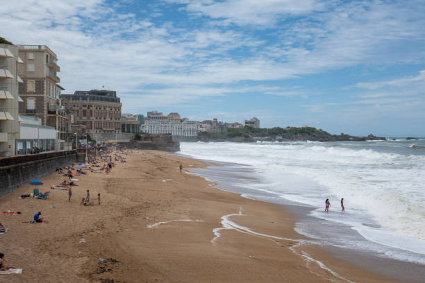 Fishing rods in action early afternoon on the Cote Basque in Biarritz with the Lighthouse and the beach in the background.