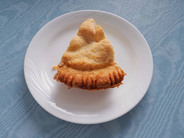 Apple pie crust detail on plate. White plate on blue tablecloth side lit.